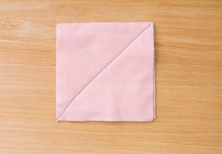 pink square of fabric with a black line drawn diagonally across